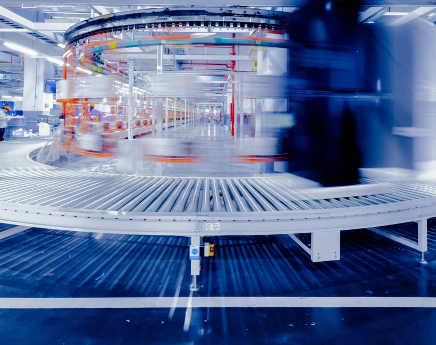 A curved roller conveyor in a bright, automated production hall
