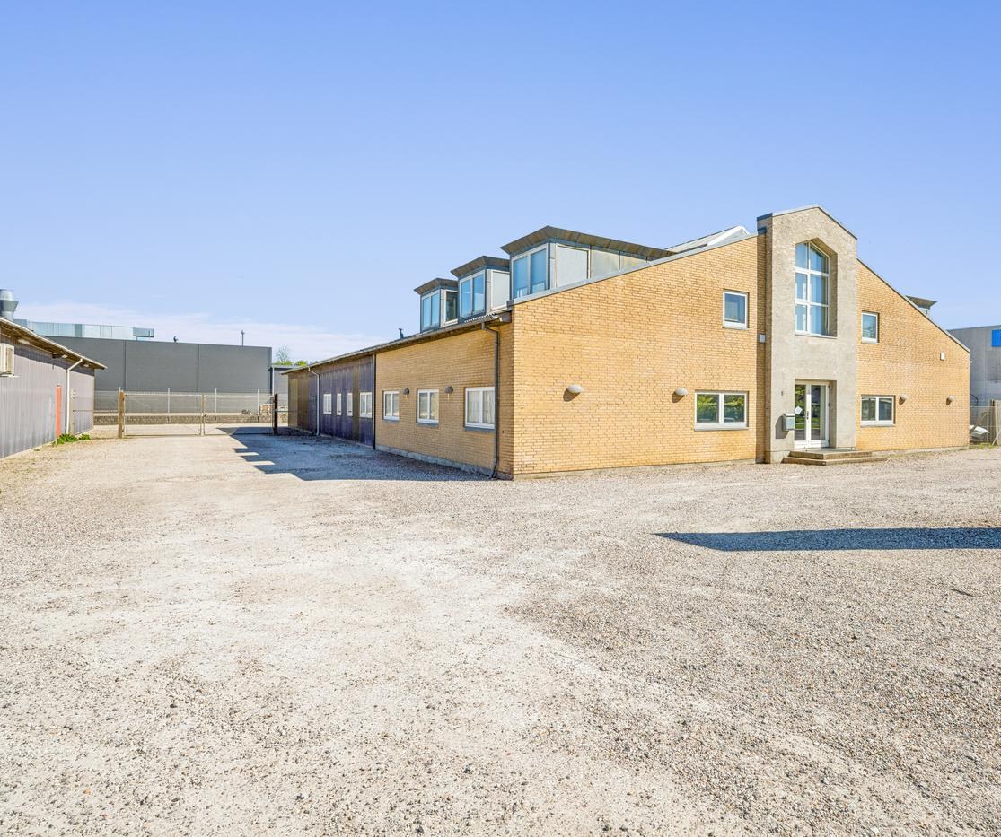 The gravel yard at Landbrugsvej 6 looking towards the glazed entrance of the office building